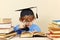 Little professor in academic hat reading an old books with magnifying glass