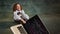 little programmer. Emotional little girl with curly hair in vintage blouse pulls laptop over dark green background