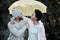 A little rain wont stop us from going on an adventure. a young couple standing under an umbrella.