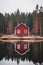 Little red cabin in the woods on a reflective lake. Lone house reflection in the winter forest.