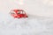 Little red car toy stuck in snow.