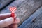 Little red clothespin heart in a man`s hand. On a wooden background. Love