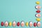 Little red Easter eggs arranged alternately with Easter candies designed as egg white with yolk on an aqua menthe surface