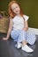 Little red-haired girl with a basket of flowers posing on an olive background. Spring portrait of a redhead girl with blue eyes.