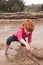 Little red haired girl building a sand castle with wet sand at a