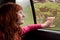 Little red haired girl looking out car window on a rainy spring day