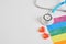 Little red hearts, medical stethoscope and lgbtq community flag on gray background copy space