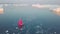 Little red sailboat cruising among floating icebergs in Disko Bay glacier during midnight sun season of polar summer. Greenland