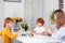 Little redhead boys with a nanny or mother or teacher sit at the table and paint with colors