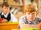 Little redhead schoolboy behind desk