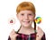 Little redheaded girl with freckles holding colored candies in hands