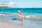 Little running girl with flying kite on tropical beach. Kid play on ocean shore.