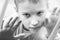 Little sad boy looks out the window. Black and white photo of a close-up child. Hungry child with big clear eyes eating bread