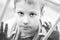 Little sad boy looks out the window. Black and white photo of a close-up child. Hungry child with big clear eyes eating bread