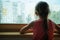 Little sad girl pensive looking through the window glass with a lot of raindrops. Sadness and loneliness childhood concept image.