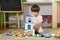 Little sad thoughtful bored toddler boy playing colorful building blocks alone at home during quarantine. development game.