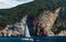 Little sailing ship in front of red cliff at coast