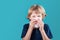 Little school boy with blonde hair sneezing to handkerchief and having runny nose. Flue, cold, allergy and disease concept