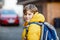 Little school kid boy of elementary class walking to school. Portrait of happy child on the street with traffic. Student