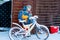 Little school kid boy of elementary class walking to school during snowfall. child removing snow from bicycle.