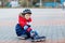 Little school kid boy skating with rollers in the city. child in protection safety clothes. Active schoolboy making