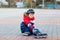 Little school kid boy skating with rollers in the city. child in protection safety clothes. Active schoolboy making