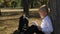 A little schoolboy is reading a book in the schoolyard, leaning against a tree