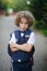 Little schoolboy stands in the school yard with an angry expression on his face .