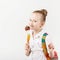 little schoolgirl with big knitted backpack eating delicious lollipop against a white background