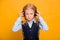 Little schoolgirl listens to music in headphones isolated on a yellow background