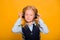 Little schoolgirl listens to music in headphones isolated on a yellow background