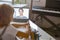 Little schoolgirl listens to teacher at videocall via laptop at table in light room