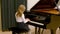 A little schoolgirl plays a classical piece of music on a piano. Young talents.