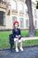 Little schoolgirl in a red beret and dress with lunch near the school. preschool child with an apple and a backpack on his first d