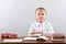 A little schoolgirl sits at a school desk