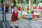 A little schoolgirl in uniform smiles happily after playing on the swing inside the school playground