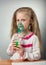 Little sick girl breathing using nebulizer, on gray