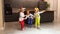 Little sister triplets in dog costumes playing and jumping in the kitchen of their house