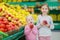 Little sisters choosing apples in a food store