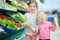 Little sisters choosing vegetables in a food store