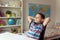 Little smart school boy making homework at desk in room