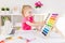 Little smiling blond girl sitting at the white desk and counting on the colourful abacus in the classroom. Preschool education