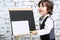 Little smiling boy in bow tie stands next to chalk board