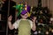 A little smiling boy wearing harlequin hat standing on background of New Year tree.