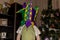 A little smiling boy wearing harlequin hat standing on background of New Year tree.