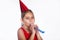 Little smiling funny girl with birthday hat and whistle on white background.