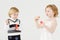 Little smiling girl and boy blow bubbles on white