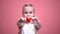 Little smiling girl with braids showing toy heart at camera closeup, charity