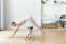 Little smiling girl crawls under her mom while she does her morning exercise