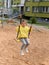 A little smiling girl enjoying swinging in a playground of an apartment house`s court yard